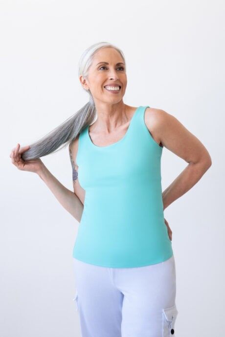 An elegant lady with gray hair wearing an aqua wave scoop neck tank top.